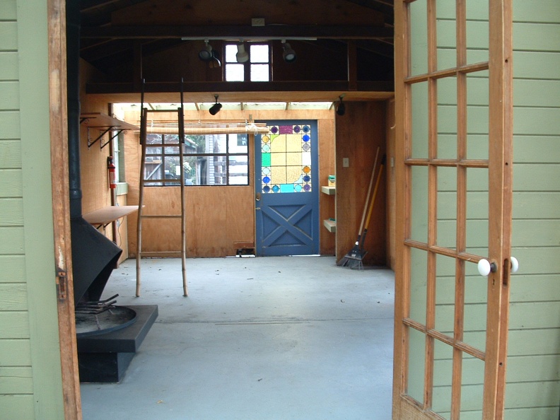 standing in atrium looking through studio. stove on left, house in distance
